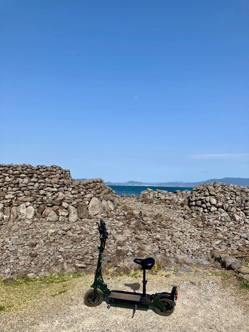 相島の史跡を背景にキックボードが置かれている風景